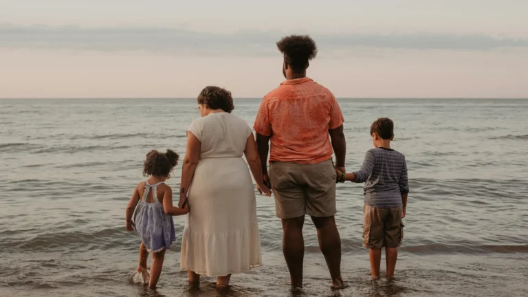 Family with two children standing at the water's edge on a beach