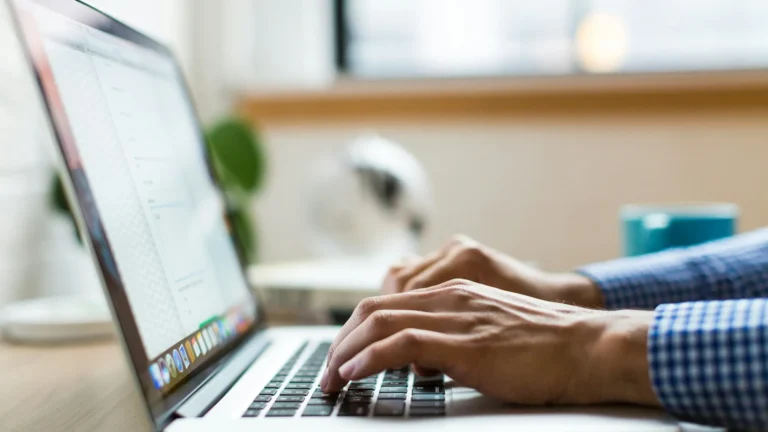 Hands typing on a laptop in an office