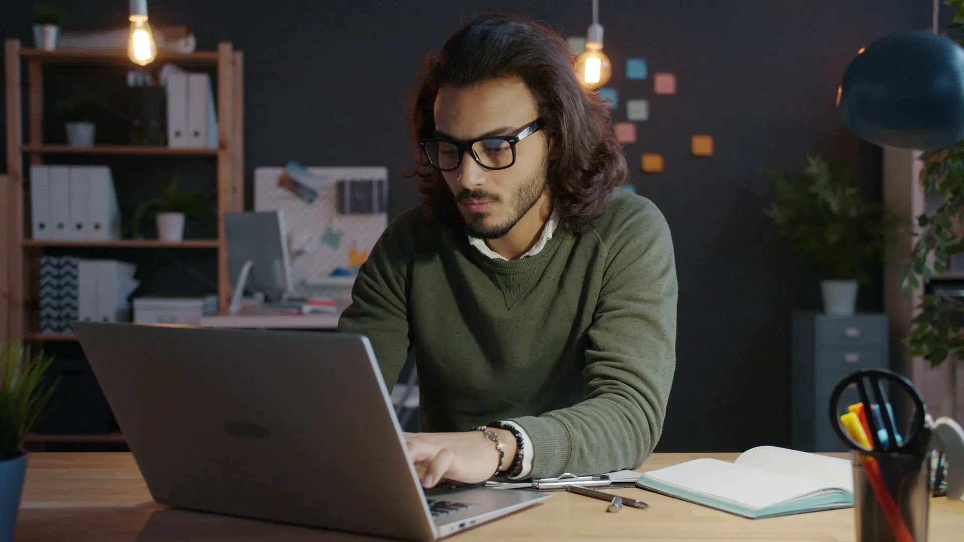 Man working on a laptop in a dimly lit office
